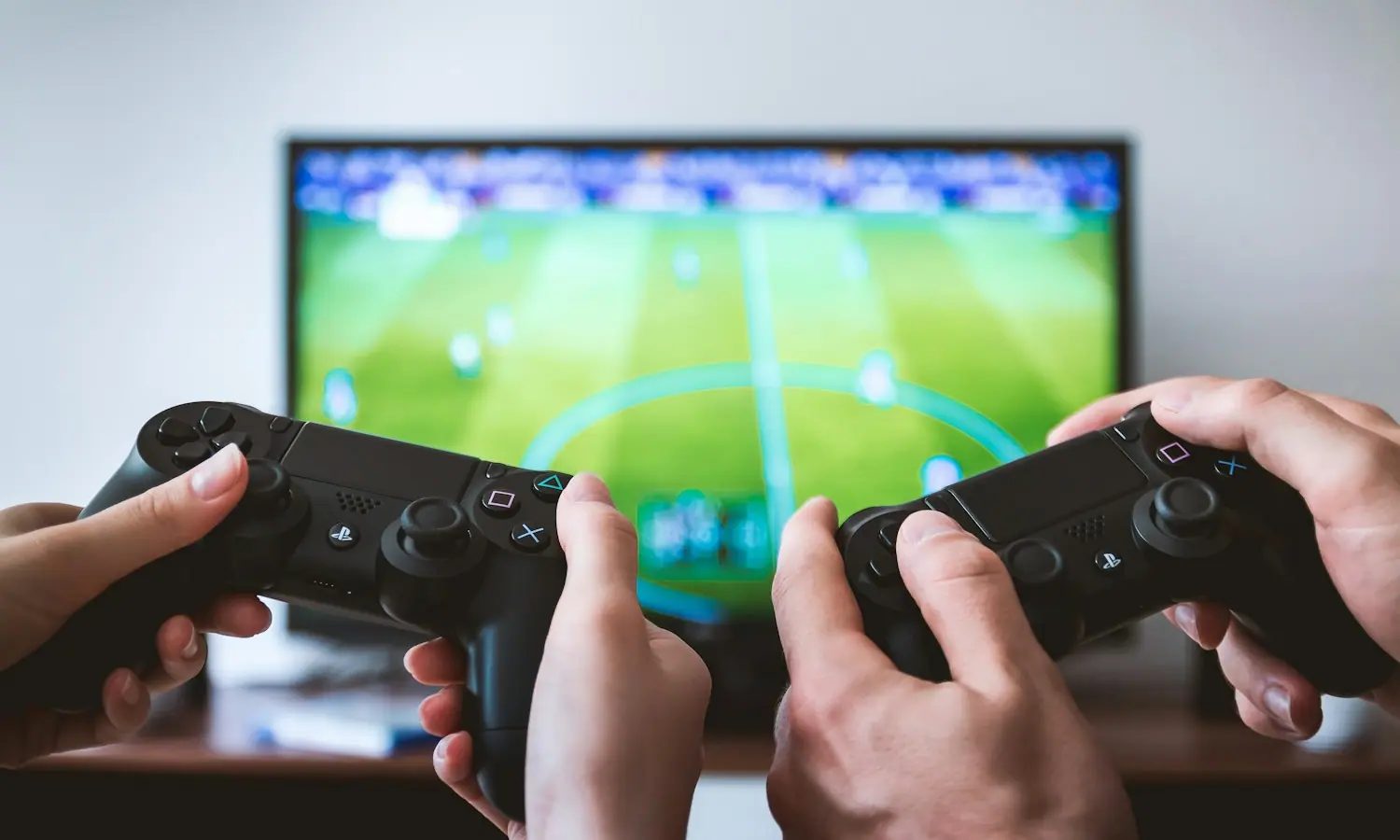 Duas pessoas a jogar com comandos, ecrã ao fundo